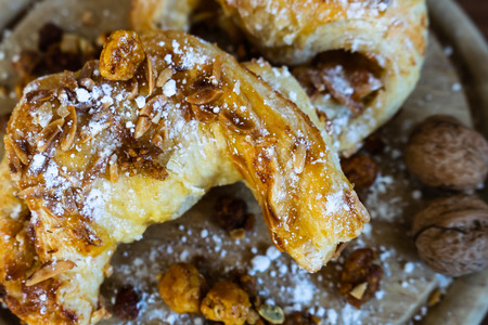 Almond croissants with powdered sugar and nuts on a wooden boardの写真素材