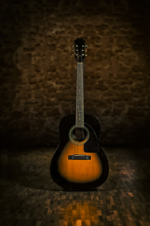 Acoustic guitar in retro environment with stonewall and wooden floor.の写真素材