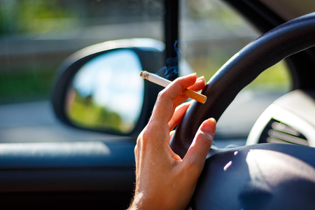 Woman smoking a cigarette at the wheel of a car.の写真素材