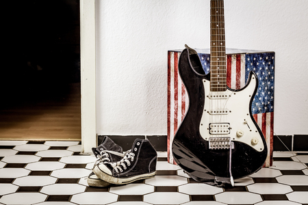 Electric guitar, leather jacket and sports shoes lying on the floor.の写真素材