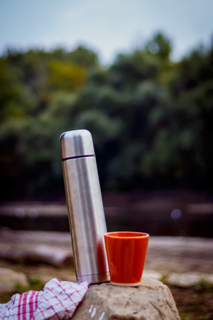 bottle and cup at an autumn picnic by the river..の写真素材