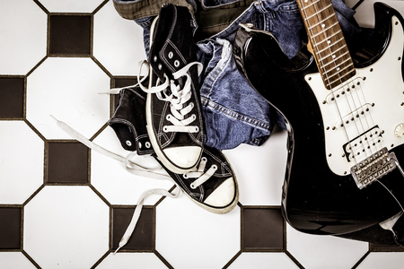 Electric guitar, leather jacket and sports shoes lying on the floor.の写真素材