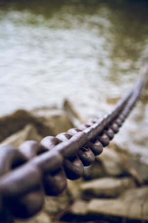 Old, dirty and heavy iron chain on the riverbank.の写真素材