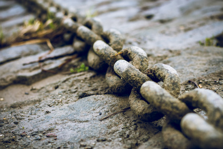 Old, dirty and heavy iron chain on the riverbank.