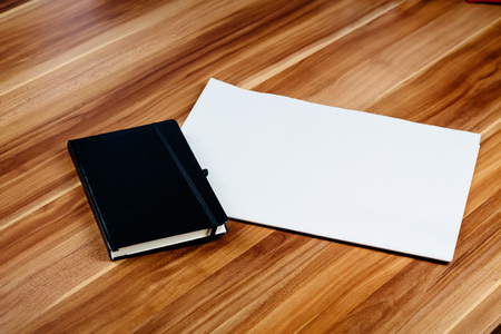 Blank newspaper and notebook on a brown wooden table.の写真素材