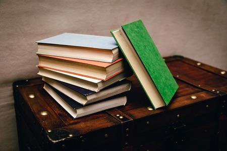 A bunch of old, dirty books on a wooden chest.の写真素材