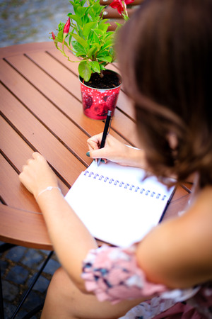 Young woman writes in the summer garden in a notebook or diary.の写真素材
