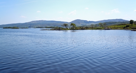 A calm lake surrounded by green hillsの写真素材