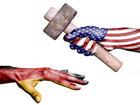 Flag of United States overprinted on a hand holding a heavy hammer hitting a hand representing the Germany. Conceptual image for political, fiscal or social aggressions, penalties, taxationの写真素材