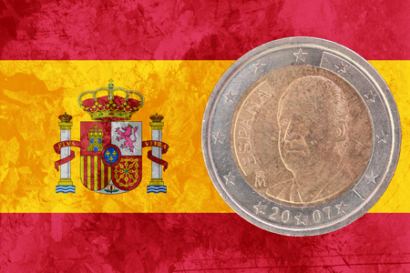 Two euros coin from Spain isolated on the national spanish flag as backgroundの写真素材