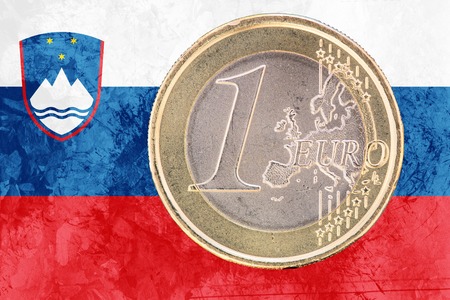 Common face of one euro coin from Slovenia isolated on the national slovene flag as backgroundの写真素材