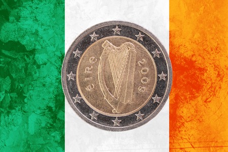 Two euros coin from Ireland isolated on the national irish flag as background