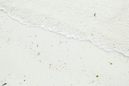Background of sandy white coastline with foam water from a tropical beach. Can be used as texture or background.の写真素材