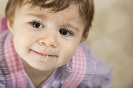 Close-up of cute one year old kid with brown eyes looking away sadly