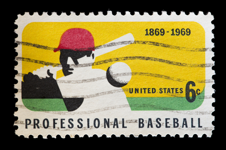 UNITED STATES OF AMERICA - CIRCA 1969: A used postage stamp printed in United States shows a professional baseball player while hitting the ball with the bat, circa 1969の写真素材