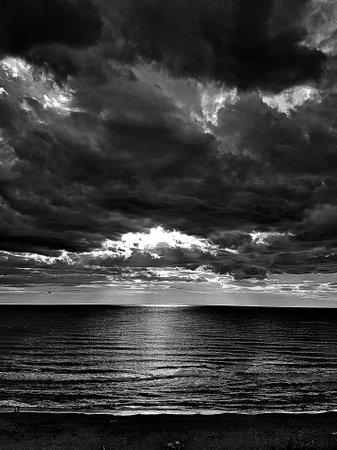 Menacious clouds with reflections on the sea.の写真素材