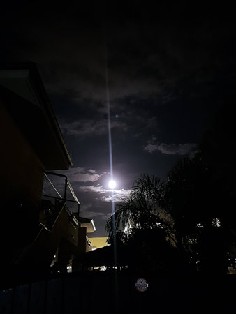 Reflection of full moon and clouds illuminated above shaded villages.の写真素材