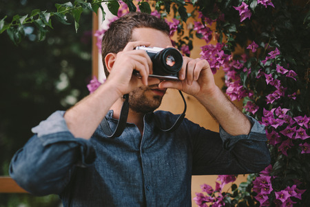 Male Photographer With Camera in front of Purple Flowers