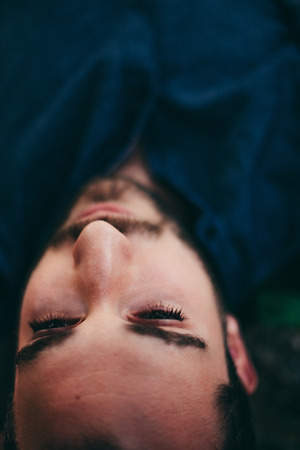 Beauty Man Portrait Lying on a Stone Between Green Natureの写真素材
