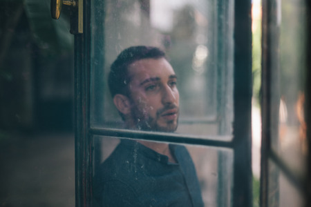 Beautiful Man Watching Through Dirty Windowの写真素材