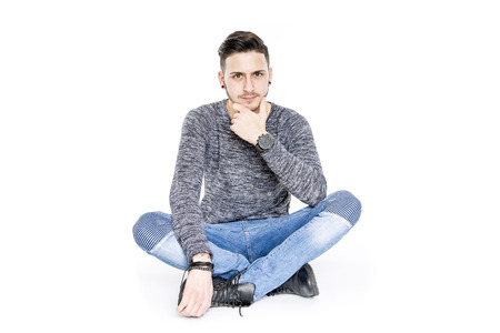 casual young brunette man sitting on floor  portrait smiling - isolated in white Background studioの写真素材