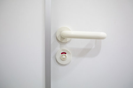locked bathroom door with red sign shows someone is inside the cabin and need some privacy to relieve, thats why the person turned to knob to lock the entrance of the wcの写真素材