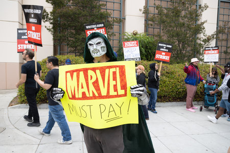 Writers Guild of America Strike 2023 in Los Angeles - The unions representing thousands of movie and television writers went on strike, bringing much production to a halt while man with mask hold signのeditorial素材