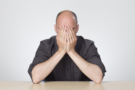 Stressed man sitting at empty deskの写真素材