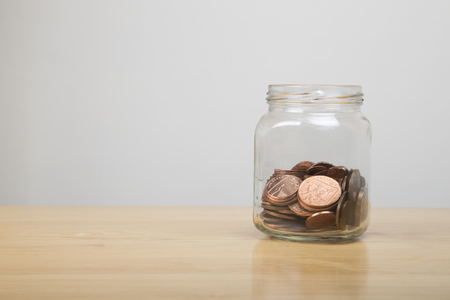 glass jar half full of low value british coinsの写真素材