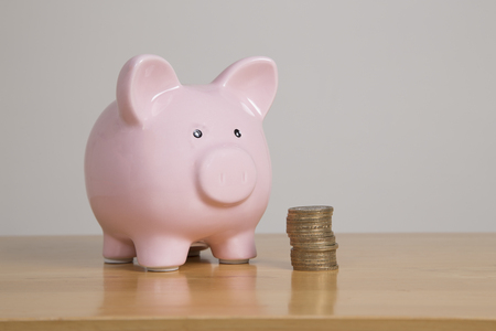 Traditional pink piggy bank on table with two pound coinsの写真素材