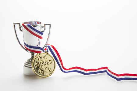 Gold medal with ribbon wrapped around a silver trophyの写真素材