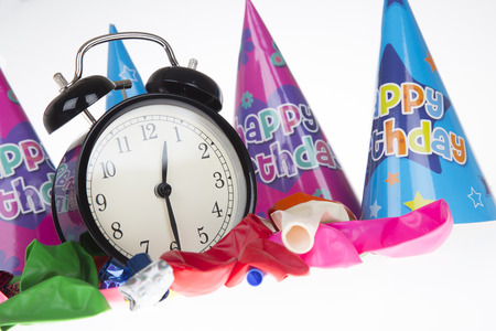 Low angle view of alarm clock surrounded by ballons and party hatsの写真素材
