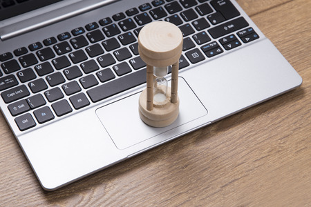 Egg timer on an open laptop keyboard in a high angle view conceptual of measurement of time and...