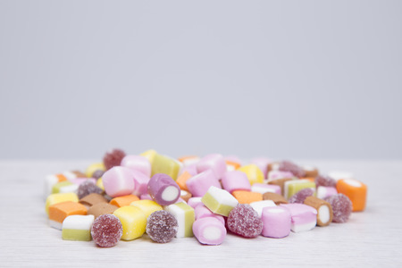 Pile of colorful diverse soft and chewy candies on grey with copy space for your text or advertisingの写真素材
