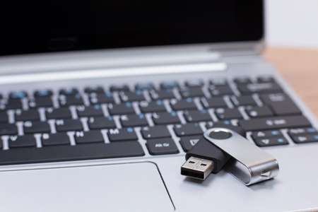Open flash drive memory stick lying on a laptop computer providing extra portable removable memory storage with select focus to the USB deviceの写真素材