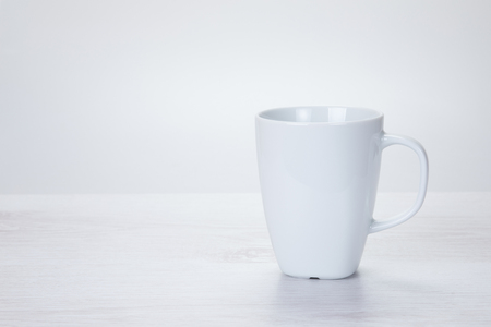 Plain white generic ceramic coffee mug on a textured off-white background with copy space alongsideの写真素材