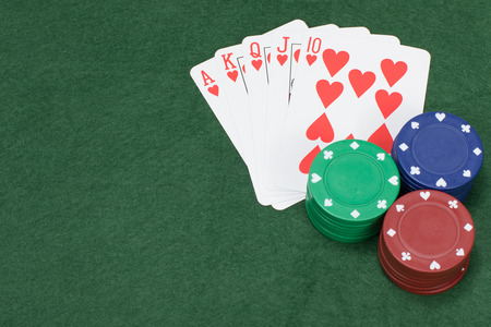 Poker chips colored green blue and red on felt covered table beside five playing cardsの写真素材