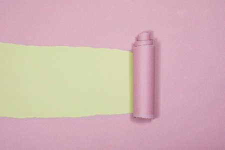 Colored paper abstract background pattern and texture with a rough cut or torn strip of purple coiled up in a spiral to reveal green beneathの写真素材