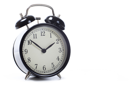Round retro black alarm clock with bells on a white background with copy space in a conceptual imageの写真素材