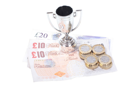 Winners silver sports trophy with cash prize in the form of pound banknotes and coins in a concept of competition and success over whiteの写真素材