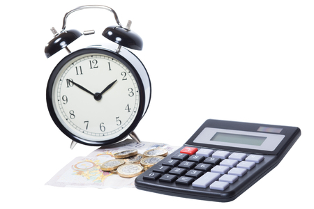 Still life of an alarm clock with a pile of pound banknotes and coins together with a calculator on white in a financial conceptの写真素材