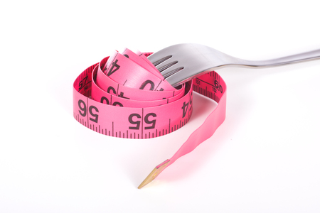 Fork with coiled red measuring tape marked in inches, close-up isolated on white background, symbolising loosing weight fitness dietの写真素材