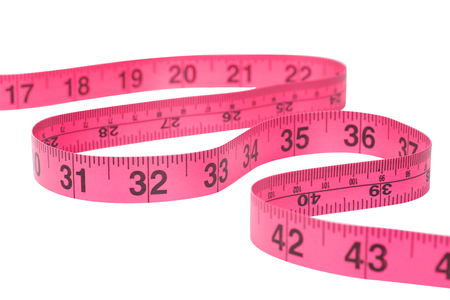 Snaking winding red measuring tape marked in inches on white in a dieting and weight loss or needlecraft conceptの写真素材