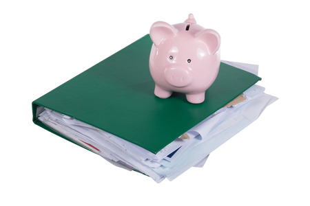 Piggy bank on a full green office binder in a business or college education financial concept isolated on whiteの写真素材