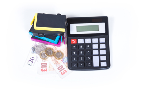 Cost of printer cartridges concept with stack of color ink consumables and simple calculator over GBP cash money, viewed from above and isolated on white backgroundの写真素材