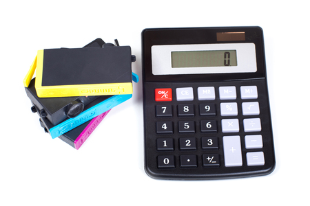 Stack of jet-ink printer cartridges and simple calculator viewed from above isolated on white background. Concept symbolising cost of consumables expensesの写真素材