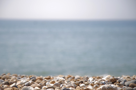 Blurred ocean view with pebbles on the seashore close-up in foreground. Natural background conceptの写真素材
