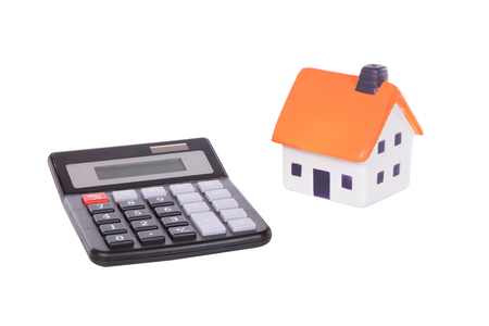 An isolated calculator and model toy house as separate objects for property, business, accounting or costs conceptsの写真素材