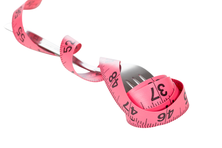 Fork wrapped in a measuring tape in a concept of controlling food intake in a dieting and weight loss conceptの写真素材