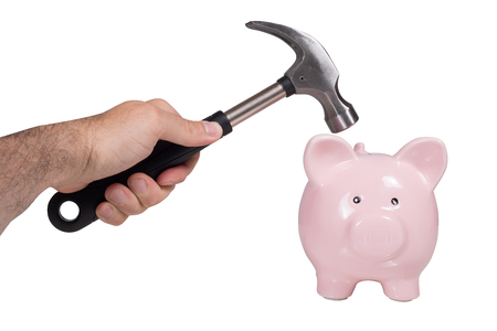Man holding a hammer over a piggy bank in a conceptual image of breaking it to raid his savings or in a DIY, renovations and home improvements conceptの写真素材